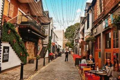 a cobblestone street with people sitting at tables in an alley at The West End Retreat - Your Luxurious 5* Apartment in Glasgow