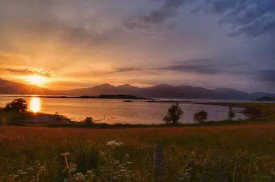 a sunset over a body of water with mountains at The Airds Hotel and Restaurant in Port Appin