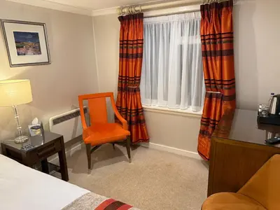 a room with a bed and a chair and a window at The Airds Hotel and Restaurant in Port Appin