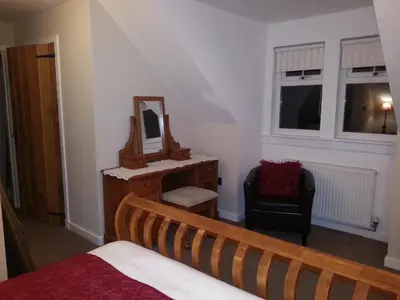 a bedroom with a bed and a mirror and a chair at Station House Lanark Bed and Breakfast in Lanark