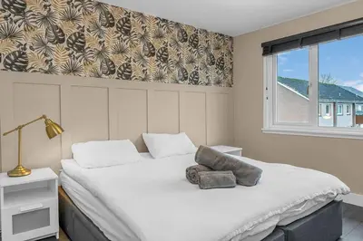 a bedroom with a large bed and a window at West Lothian 5 Beds + car space in Whitburn