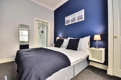 a bedroom with a large bed with a blue wall at Exclusive Use in Gourock