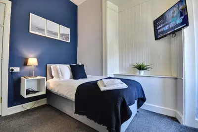 a bedroom with a bed with blue walls and a tv at Exclusive Use in Gourock