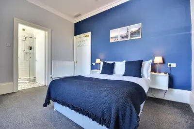 a blue bedroom with a large bed with blue walls at The Cloch in Gourock