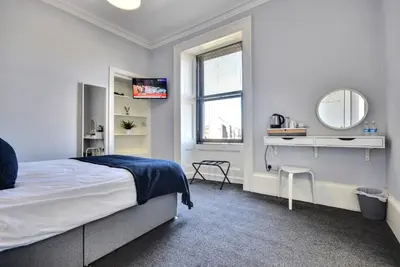 a white bedroom with a bed and a mirror at The Cloch in Gourock
