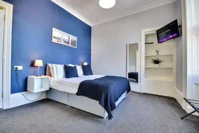 a blue bedroom with a bed and a tv at The Cloch in Gourock