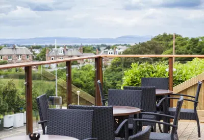 a patio with tables and chairs on a balcony at Braid Hills Hotel in Edinburgh