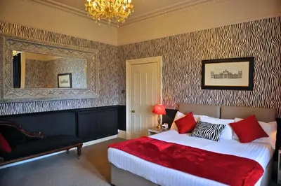 a bedroom with a bed and a mirror and a chair at Braid Hills Hotel in Edinburgh