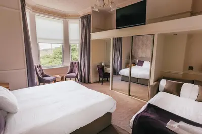 a hotel room with two beds and a mirror at Braid Hills Hotel in Edinburgh