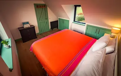 an orange bed in a room with green doors at Croft 11 Clovullin in Ardgour
