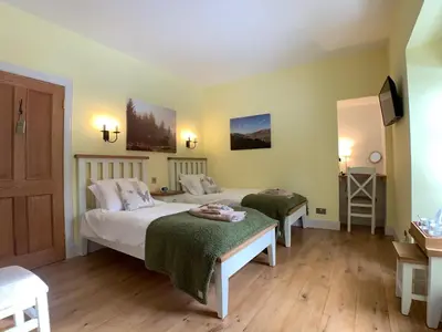 a bedroom with two beds and a television in it at Ewich House B&B in Crianlarich