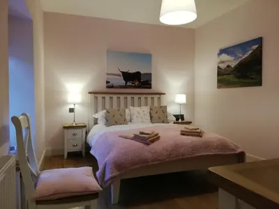a bedroom with a bed with a cow on the wall at Ewich House B&B in Crianlarich