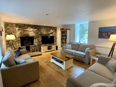 a living room with couches and a stone fireplace at Ewich House B&B in Crianlarich