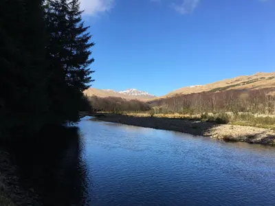 a river with trees and mountains in the background at Ewich House B&B in Crianlarich