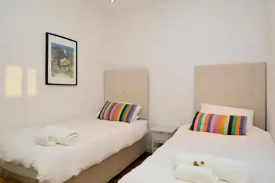 two beds in a room with white walls at Old Fire Station in Tighnabruaich