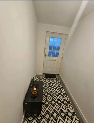 a hallway with a black table and a door at Darnley southside room in a private home 61 Leggastston Road in Pollokshaws