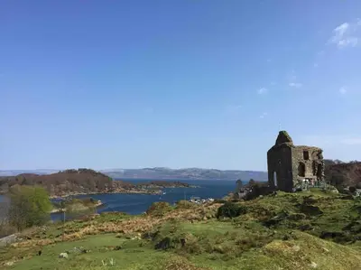 an old building on a hill with a body of water at Tarbert large, bright, 4 bedroom flat with harbour views in Tarbert