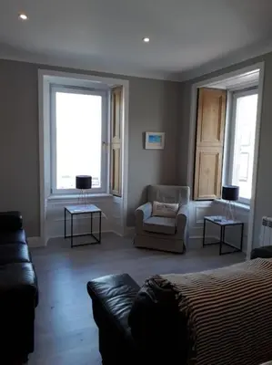 a living room with a bed and a couch and two windows at Tarbert large, bright, 4 bedroom flat with harbour views in Tarbert