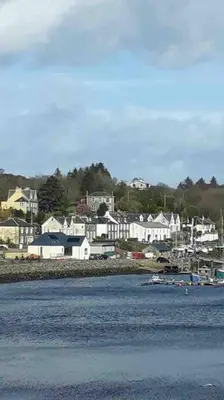 a town with white houses and boats in the water at Tarbert large, bright, 4 bedroom flat with harbour views in Tarbert