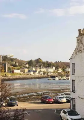 a group of cars parked in a parking lot next to a river at Tarbert large, bright, 4 bedroom flat with harbour views in Tarbert