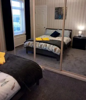 a bedroom with two beds and a mirror at Springfield Apartment - Train to Glasgow or Edinburgh - Private Parking & Wifi in Airdrie