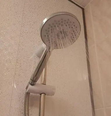 a shower with a shower head in a bathroom at Springfield Apartment - Train to Glasgow or Edinburgh - Private Parking & Wifi in Airdrie