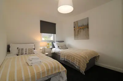 a bedroom with two beds and a lamp at Signature - Belvidere House in Glasgow