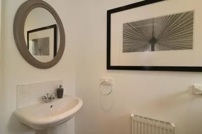 a white bathroom with a sink and a mirror at Signature - Belvidere House in Glasgow