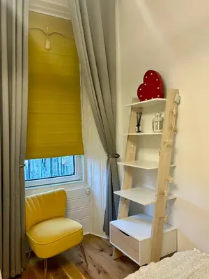 a room with a yellow chair and a shelf and a window at Glasgow Center/West End Apartment in Glasgow