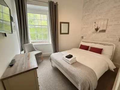 a bedroom with a bed and a chair and a window at King’s stable 2 rooms in Edinburgh