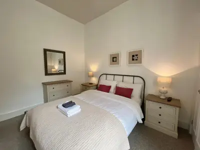 a bedroom with a white bed with red pillows at King’s stable 2 rooms in Edinburgh
