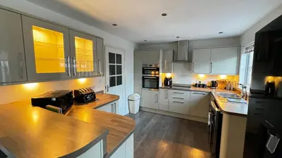 a kitchen with white cabinets and a wooden counter top at 6 Tobar Oisinn in Oban