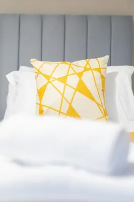a yellow and white pillow sitting on top of a bed at 2 BDR Apt By Caledonia Luxe Stays Short Lets & Serviced Accommodation Bishopton in Bishopton