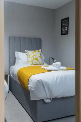 a bedroom with a large bed with a yellow blanket at 2 BDR Apt By Caledonia Luxe Stays Short Lets & Serviced Accommodation Bishopton in Bishopton