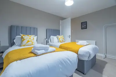 a bedroom with two beds with yellow and white sheets at 2 BDR Apt By Caledonia Luxe Stays Short Lets & Serviced Accommodation Bishopton in Bishopton