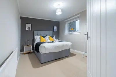 a bedroom with a bed with yellow pillows and a window at 2 BDR Apt By Caledonia Luxe Stays Short Lets & Serviced Accommodation Bishopton in Bishopton