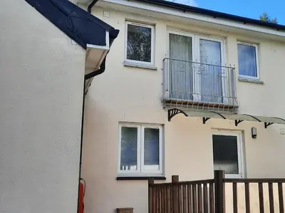 a white house with a balcony and a fence at 1 Bed in Inveraray 91310 in Crarae