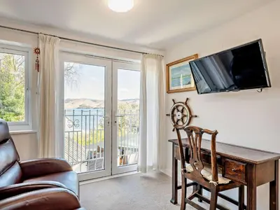 a living room with a desk and a tv and a balcony at 1 Bed in Inveraray 91310 in Crarae