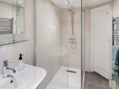 a white bathroom with a sink and a shower at Corner Cottage in Girvan