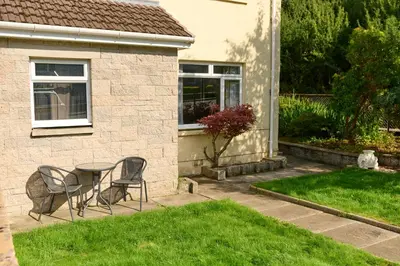 a patio with two chairs and a table in front of a house at Charming 2BD House - Parking & Garden in Oban in Oban