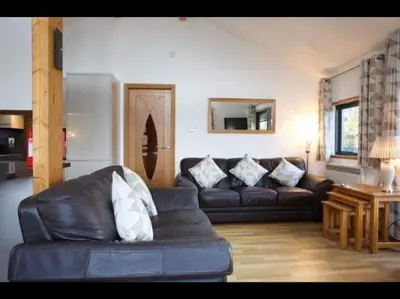 a living room with a leather couch and a table at The Crannog on Loch Tay in Morenish