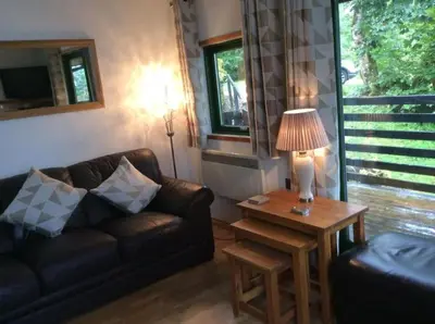 a living room with a couch and a table with a lamp at The Crannog on Loch Tay in Morenish