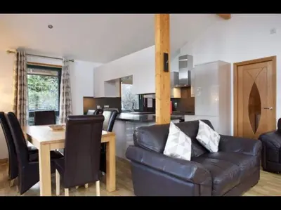 a living room with a leather couch and a table at The Crannog on Loch Tay in Morenish