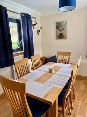a dining room table and chairs in a room with a table and blue curtains at Scottish Highland house Fort William in Corran