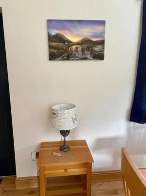 a lamp on a table with a painting on the wall at Scottish Highland house Fort William in Corran