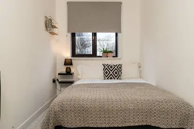 a bedroom with a large bed with a window at Stylish City Pad with Free Private Parking in Glasgow