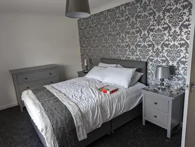 a bedroom with a bed with a book on it at Lovely 2 Bedroom Terrace House in Coatbridge