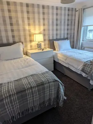 a bedroom with two beds and a table with a lamp at Lovely 2 Bedroom Terrace House in Coatbridge