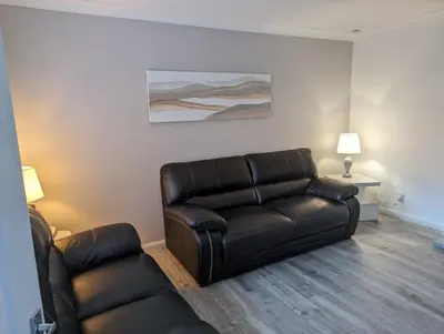 a living room with a leather couch and a chair at Lovely 2 Bedroom Terrace House in Coatbridge