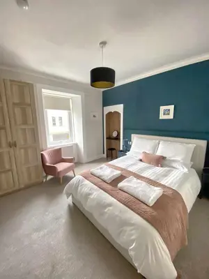 a bedroom with a large bed with a blue wall at Waverley Apartments, The Wheelhouse in Gourock